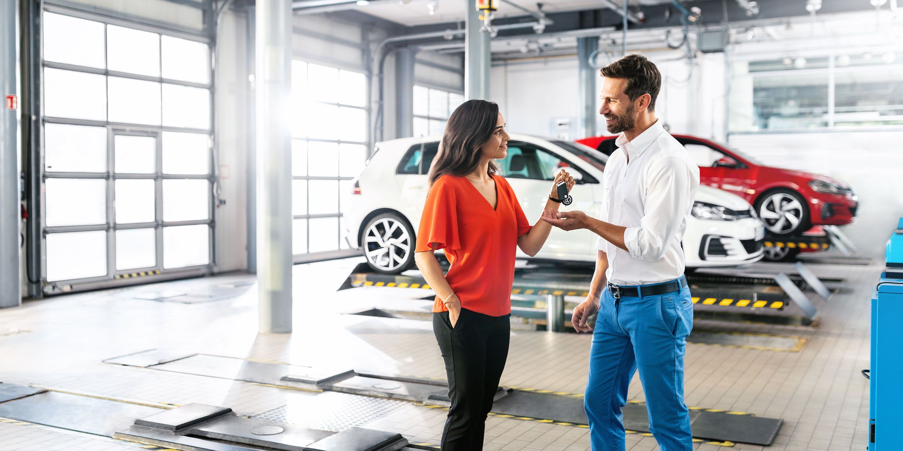 Eine Frau übergibt in einer VW Servicewerkstatt ihren Autoschlüssel an einen Mann