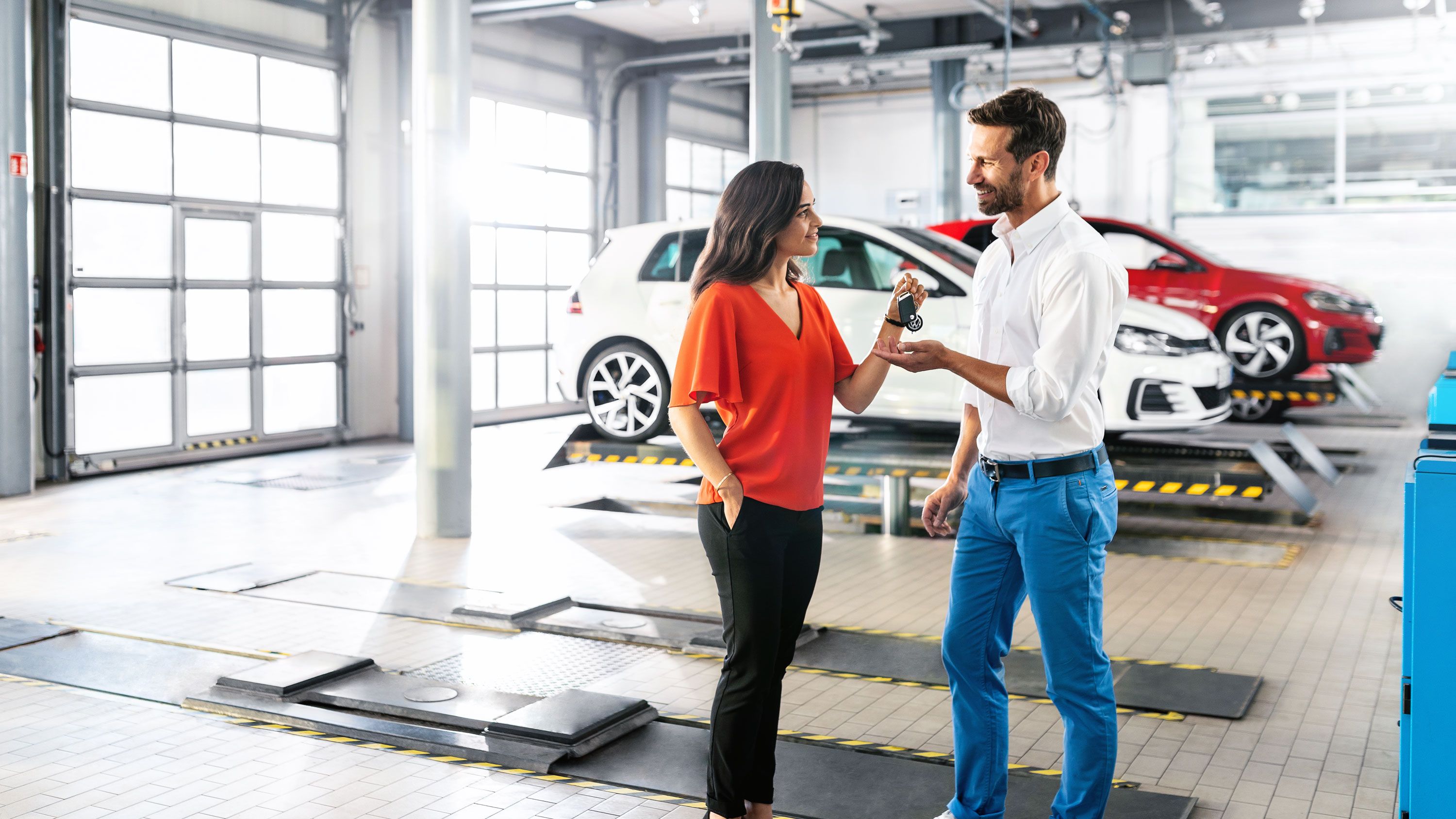 Eine Frau übergibt in einer VW Servicewerkstatt ihren Autoschlüssel an einen Mann