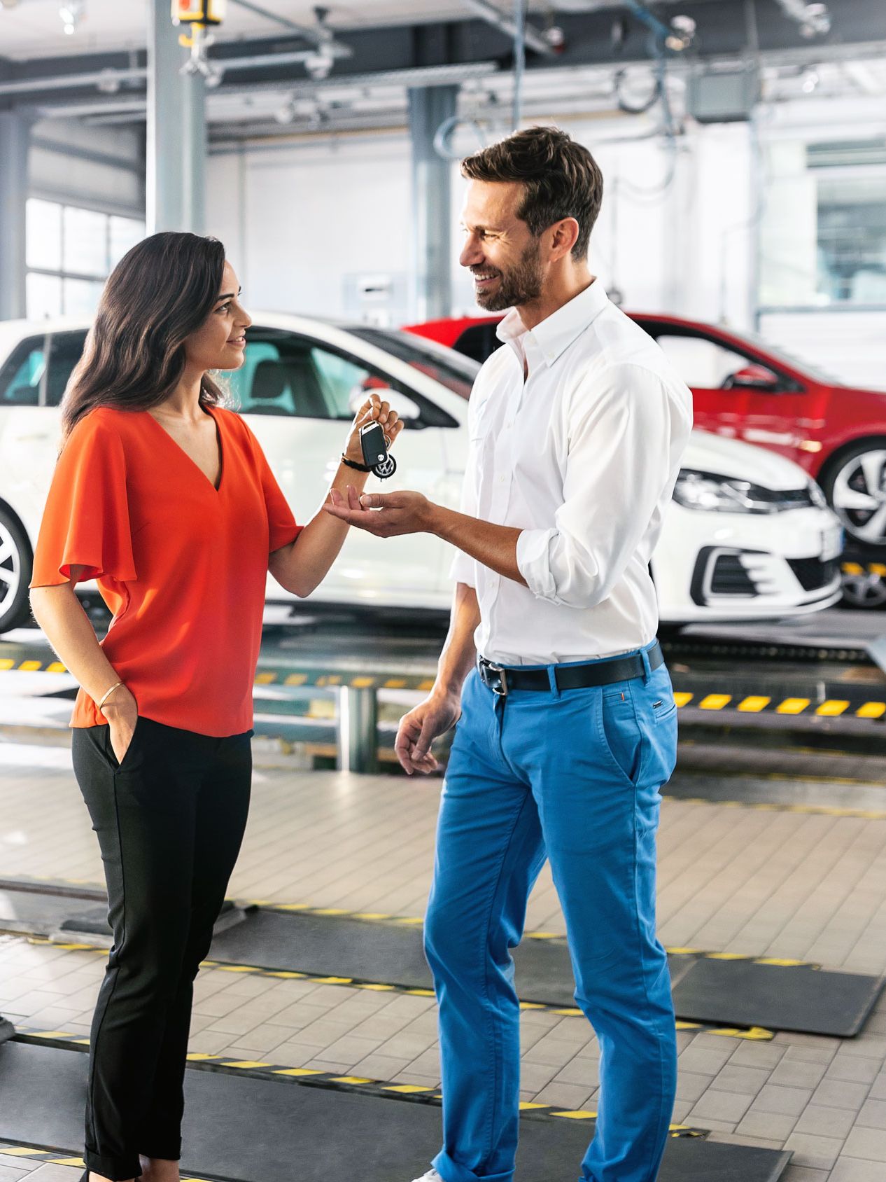 Eine Frau übergibt in einer VW Servicewerkstatt ihren Autoschlüssel an einen Mann